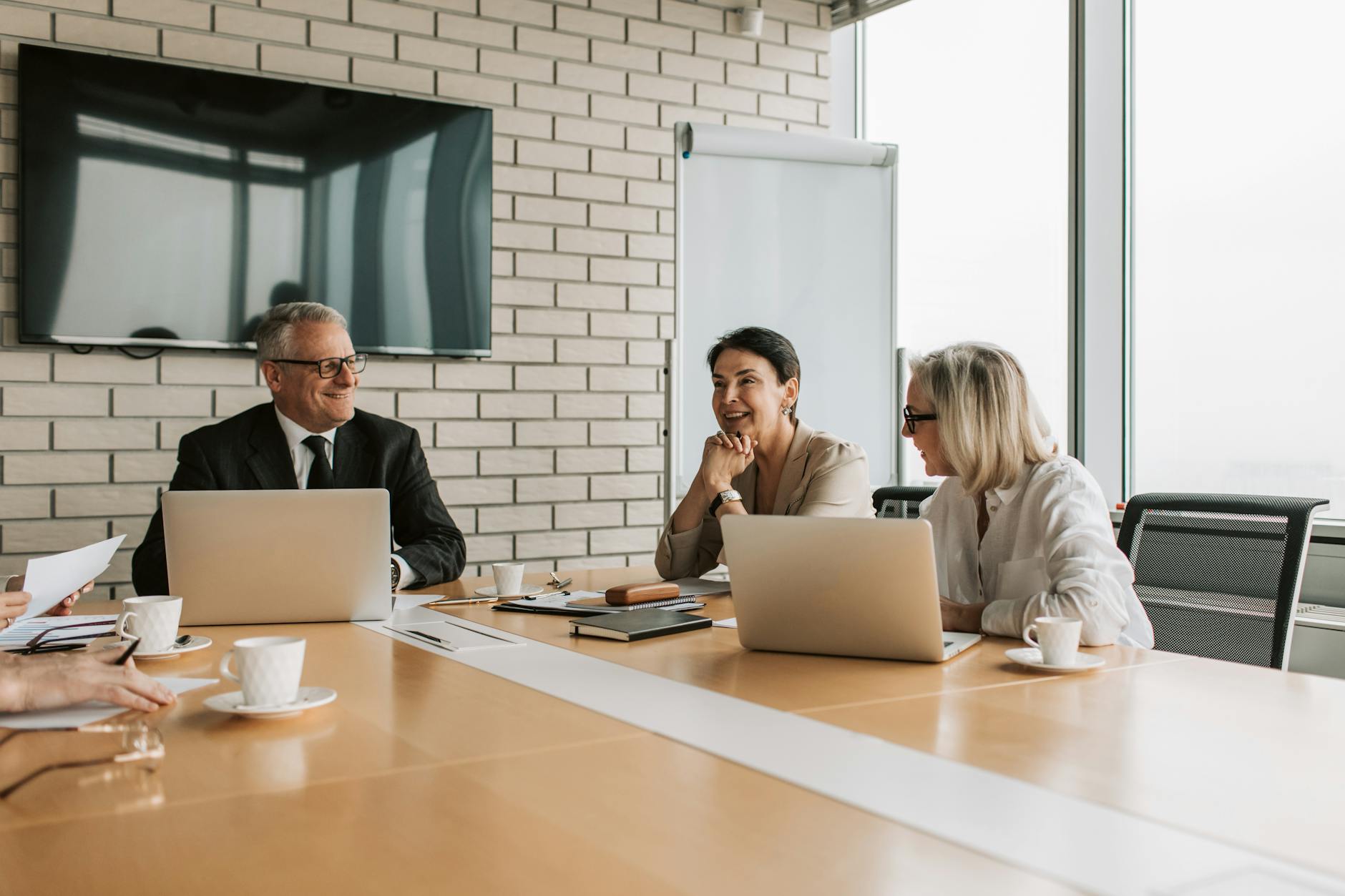 one man and two women having a meeting in a boardroom