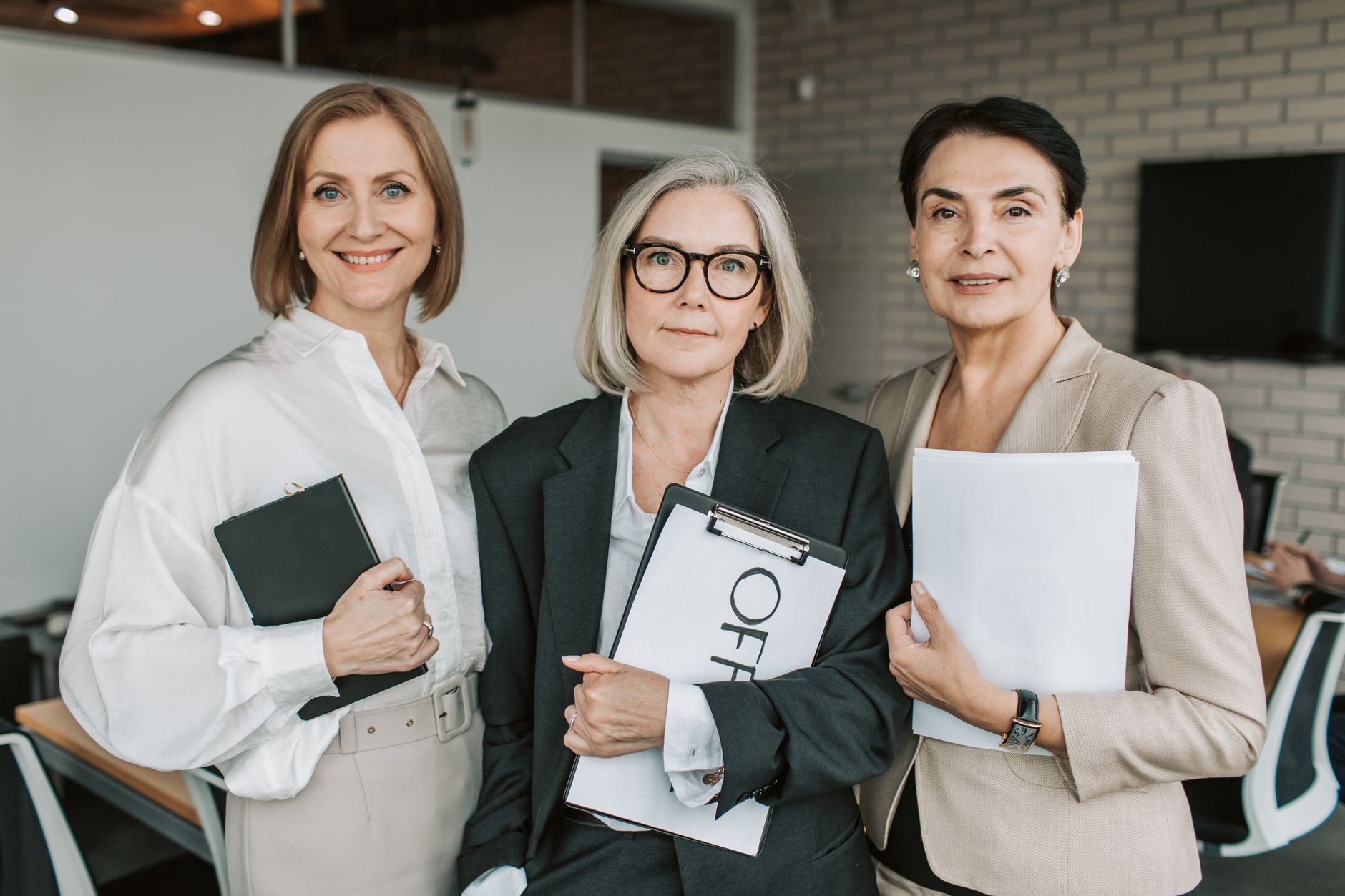 an elderly woman in black blazer standing in between her colleagues